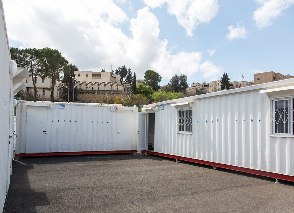 מתחם מכולות מוסבות בצבע לבן המשמשות כיחידות דיור או משרדים זמניים. פתרון מודולרי, נייד ועמיד המותאם לשטחי עבודה, מוסדות ופרויקטים זמניים.