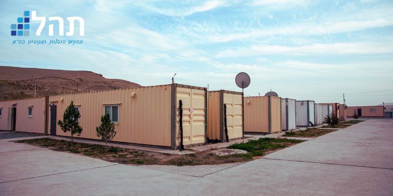 שורת מכולות מוסבות למגורים בפרויקט דיור זמני, עם חלונות, דלתות ותשתיות מלאות, מבית תהל